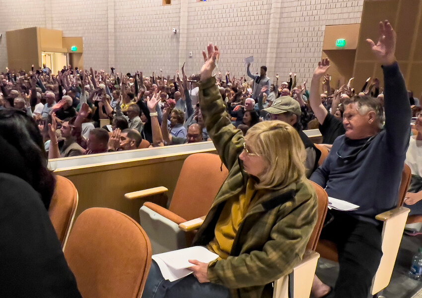 Westport voters raise their hands in approval of the school budget.