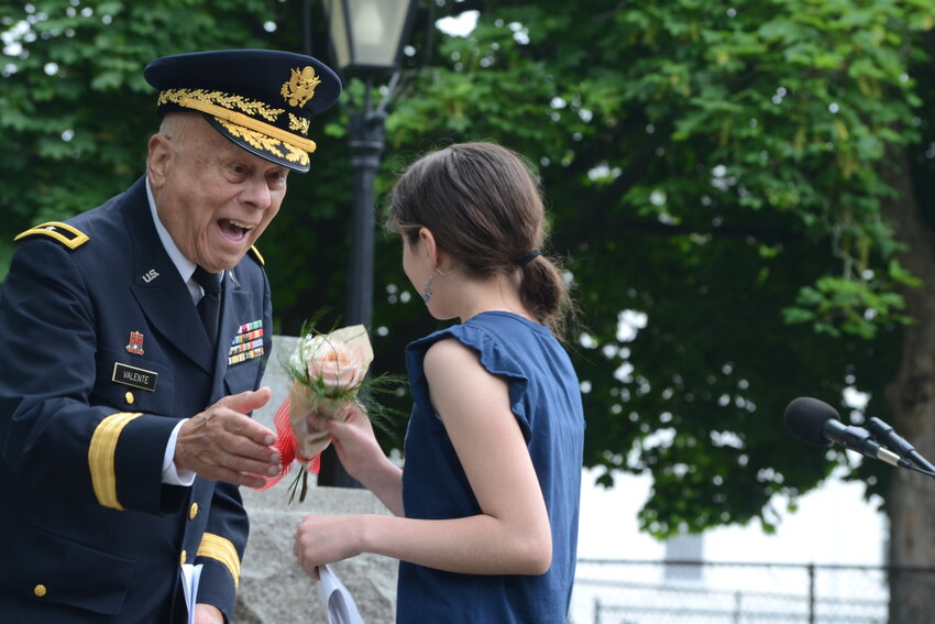 Brigadier General (Ret.) Richard Valente presents a bouquet to Willow Suplido after her reading of &ldquo;Freedom Isn&rsquo;t Free&rdquo;.