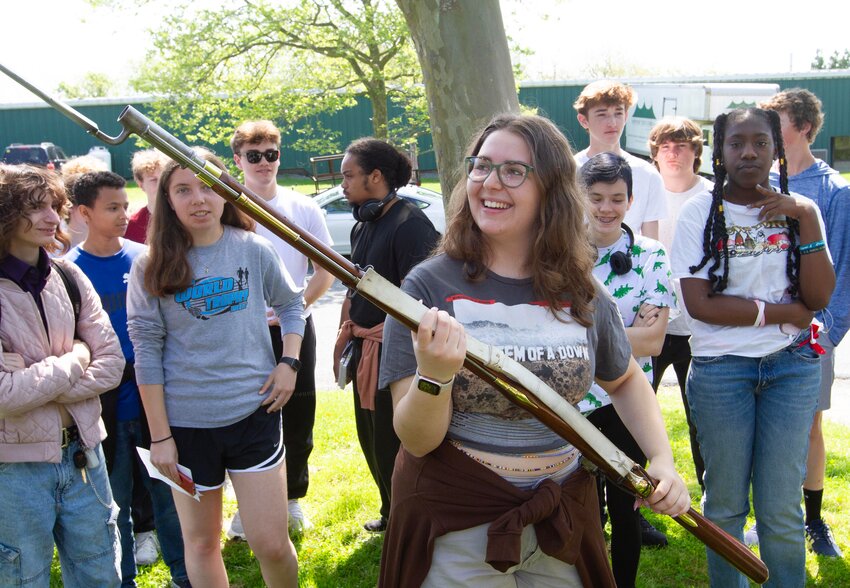 Portsmouth High School student Kiera Daly feels the weight of a British musket at Turkey Hill-Heritage Park, where Seth Chiaro of the Battle of R.I. Association (BoRIA) talked about the Battle of Rhode Island &mdash; also known as the Battle of Quaker Hill&nbsp;&mdash; between the Hessians and American revolutionists in 1778.