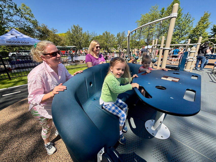 Martha Arbuthnot and her daughter, Tally, 3 (foreground), and Debbie Chappell and her granddaughter, Margaux Rando, almost 2, enjoy the Sway Fun ride. Chappell&rsquo;s niece is Kateri Chappell Buerman, who heads up the Four Hearts Foundation which raised funds for the playground.