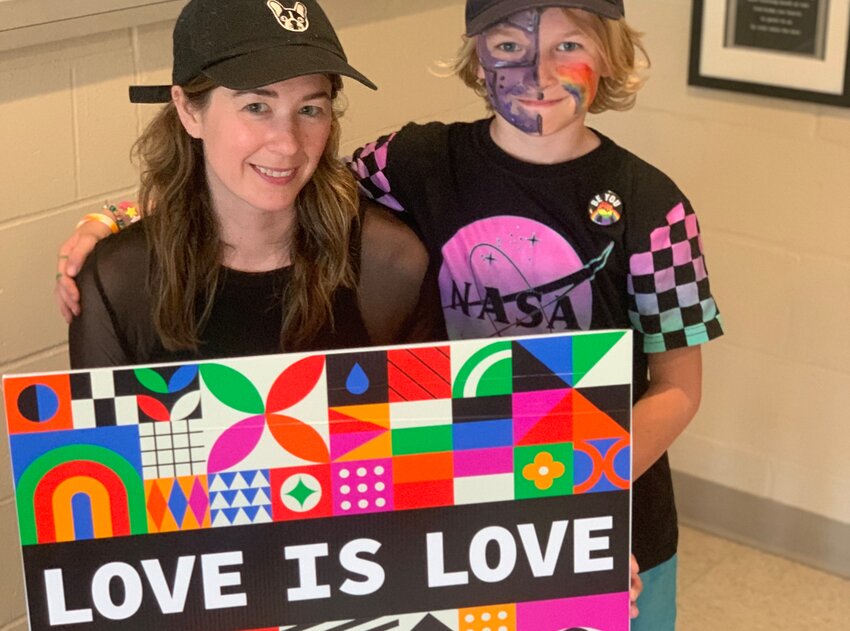 Graphic designer Erin Kinnane and her son, August Chase, a student at Wilbur &amp; McMahon School, pose with the sign Erin designed for the &quot;Love is Love&quot; initiative in recognition of Pride Month. Love Wins Coastal has organized the initiative, which encourages residents to place the signs in their yards throughout the month of June.
