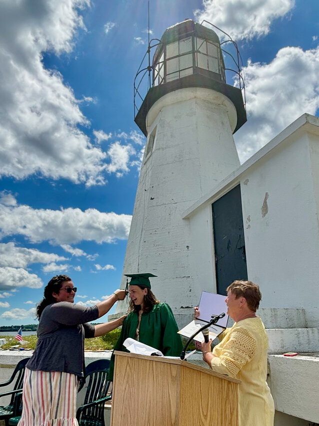 Graduating senior Marissa Vargas is all smiles as Prudence Island School teacher/advisor Stephanie Jenness turns her tassel at the conclusion of a unique one-student graduation ceremony outside Sand Point Lighthouse on the island Saturday. At right is Cathy Homan, who chairs the Prudence Island School Foundation.