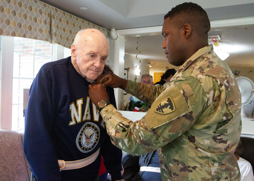 Naval veteran George Shea is pinned by Army National Guardsman Staff Sgt. Frentz Bel.
