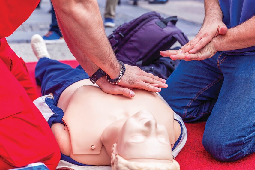 Instructor and student review the proper technique for chest compressions during a CPR training class.a