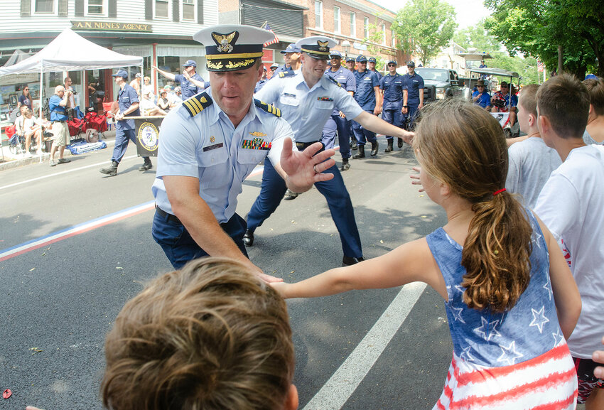 Coast Guard commander LCDR Tyler Kelley of the   USCGC William Chadwick shakes hands with parade goers on Hope Street during the Bristol Fourth of July Parade on Thursday morning.