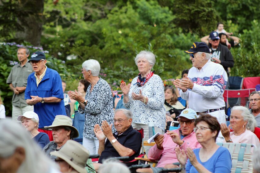 U.S. Navy veterans stand to receive applause from the crowd as The American Band plays the &ldquo;Armed Forces Salute&rdquo; to Army, Navy, Air Force, Marines Corps and Coast Guard retirees at the Friends of the Glen Manor House&rsquo;s outdoor concert on July 11.