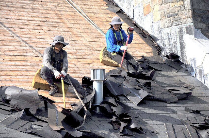 Workers from Quality Construction and Roofing Co. go to work stripping shingles.