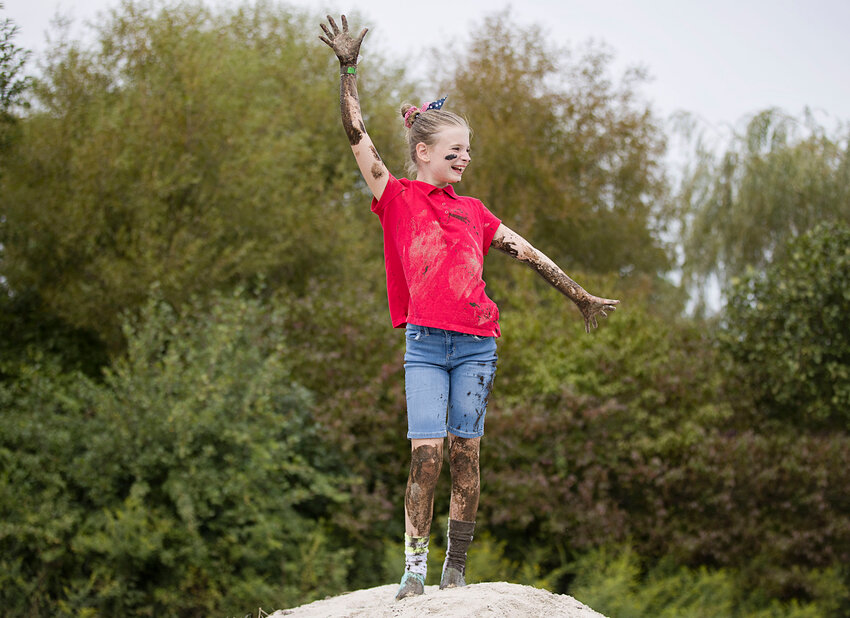 A muddy Caroline White strikes a pose at the top of a giant sand hill.