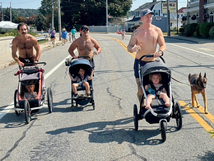 Connor Eaton (pushing Levi, 2), Kyle Jackson (with Rome, 2), and Andy Sallberg (with Odin, 2, and his dog Lyra) get some sun while running along Park Avenue during Saturday&rsquo;s Sakonnet Coastal Bike and Stroll event. Sallberg is a Portsmouth firefighter.