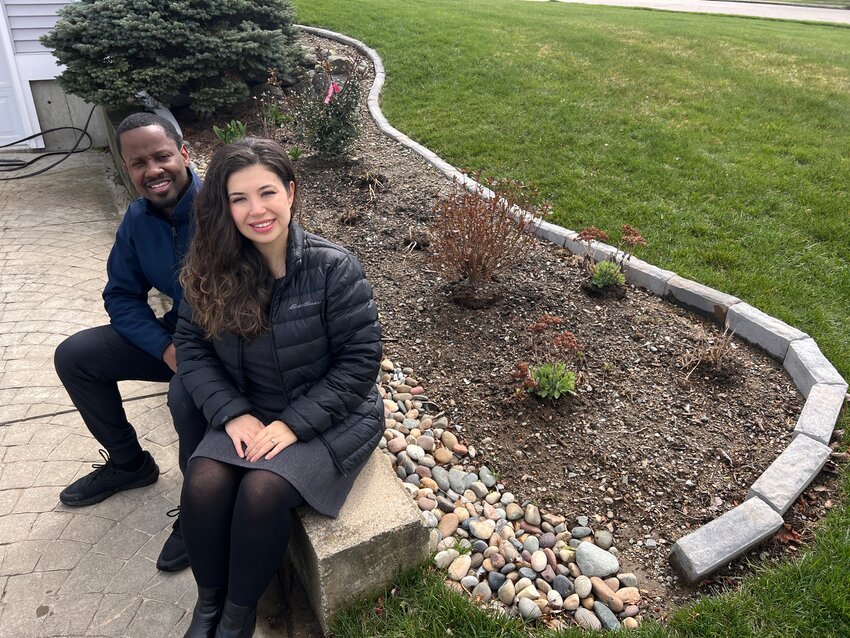 Marlon (left) and Selcan McKenzie sit in front of their rain garden, made possible through the efforts of the Eastern Rhode Island Conservation District.