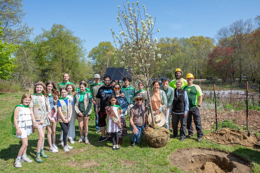 A group of volunteers, including Girl Scout Brownie Troop 485, prepare to plant a pear tree at the Barrington Farm School. The Girl Scouts wore super hero capes, given by Bartlett Tree Experts, as a reminder that even a small act like planting a tree can make a super impact in a community.