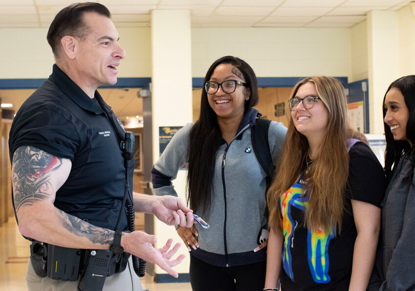 Joel Saccoccio, Barrington&rsquo;s school resource officer, confidently wears his sleeve tattoos as he chats with students in the hallway at Barrington High School.