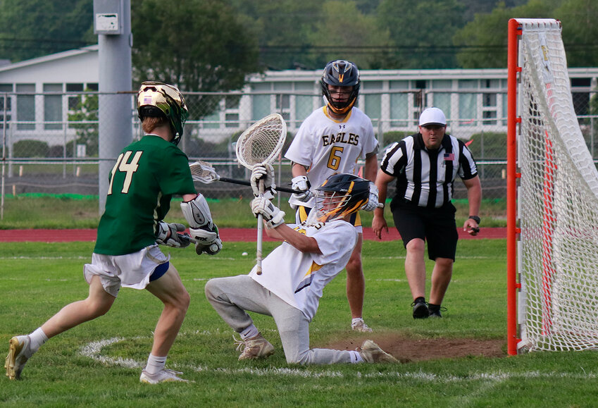 Defender Nate Kreft (middle) looks on as goalie Gavin Munzert attempts to make a save during the team's playoff loss to Hendricken.