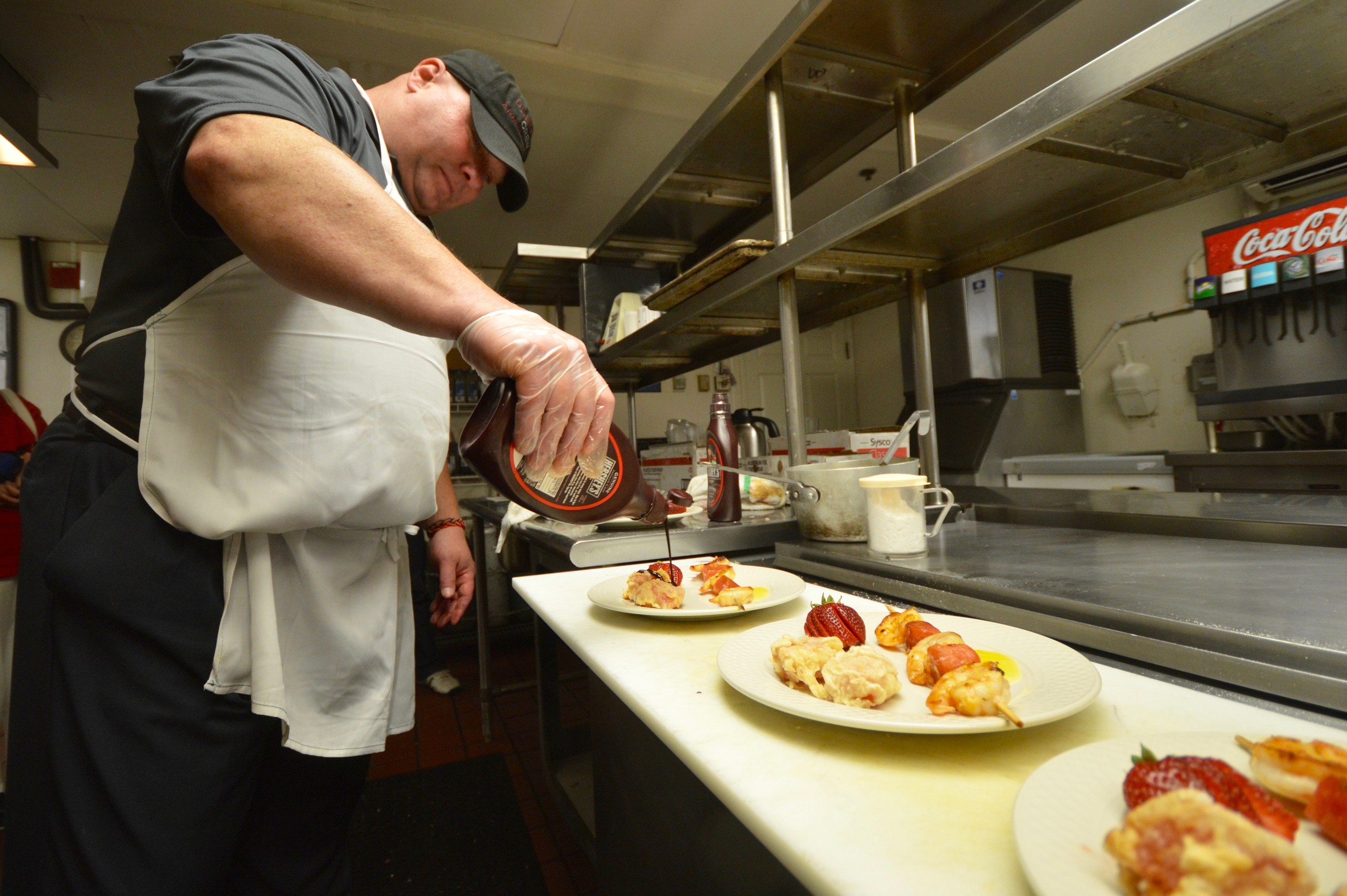 Lt. Steve Hoetzel of the Portsmouth Police Department drizzles chocolate sauce on a piece of fried watermelon. He also made grilled shrimp-and-watermelon skewers.
