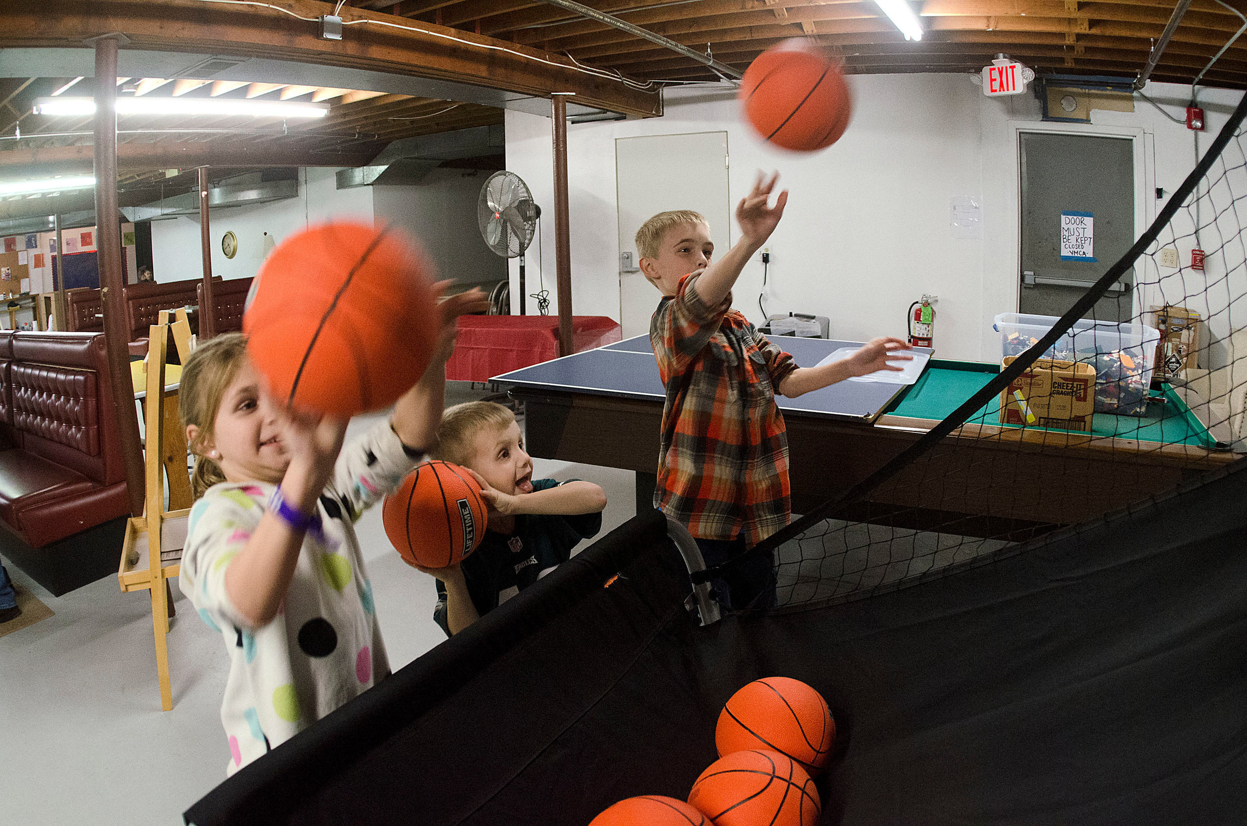 Brooke Marston, 7, Chase Marston, 5 and Jack Marston, 9 (from left), play a basketball shooting game in the basement of the Common Fence Point Community Hall. They were there for the after-school program facilitated by the Newport County YMCA.