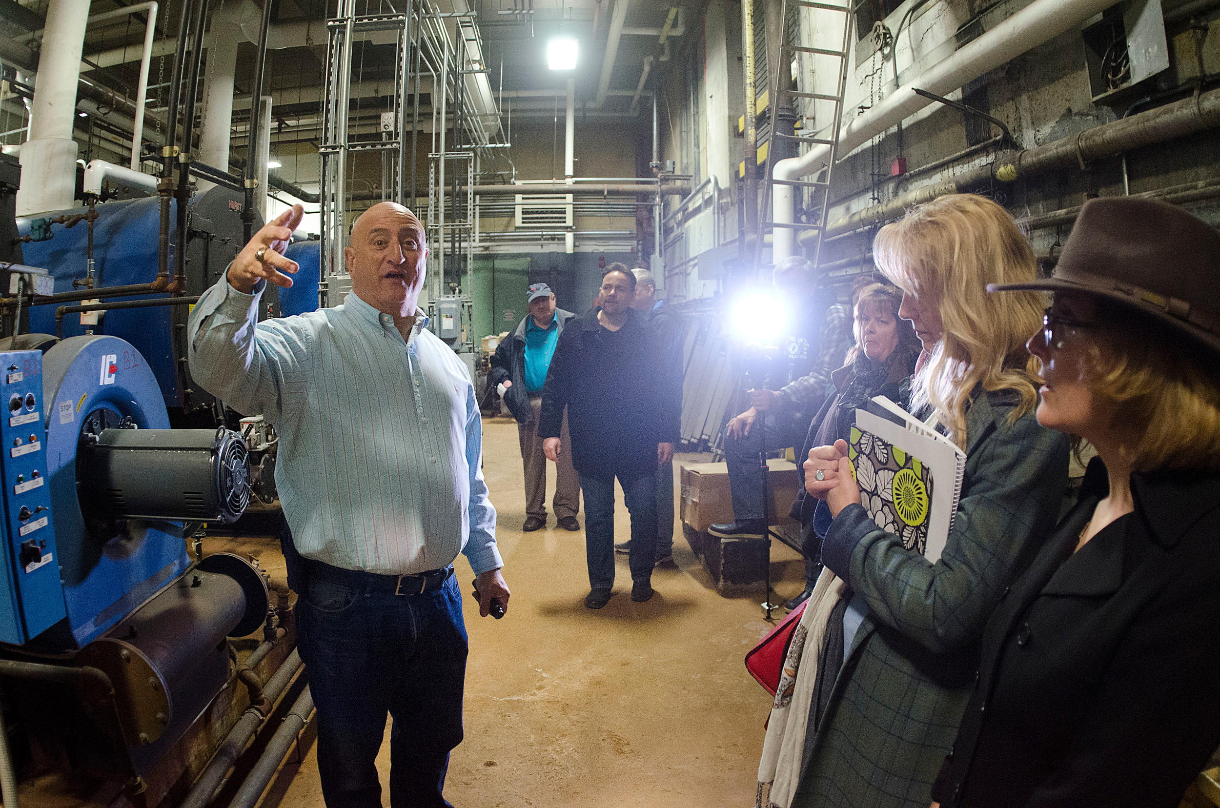 High school facilities director Tony Feola gives a tour of the school's boiler room to school committee and city council members. He explains that their is standing water underneath the boiler room.