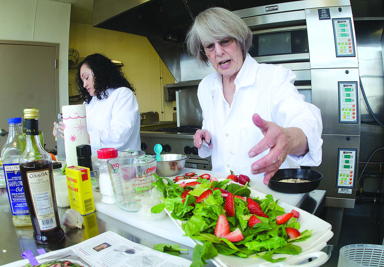 Mary Hughes (right) and Rosa Munoz of Savory Fare prepare Spring Strawberry Salad and Garlic Shrimp Kabobs for delivery to customers.