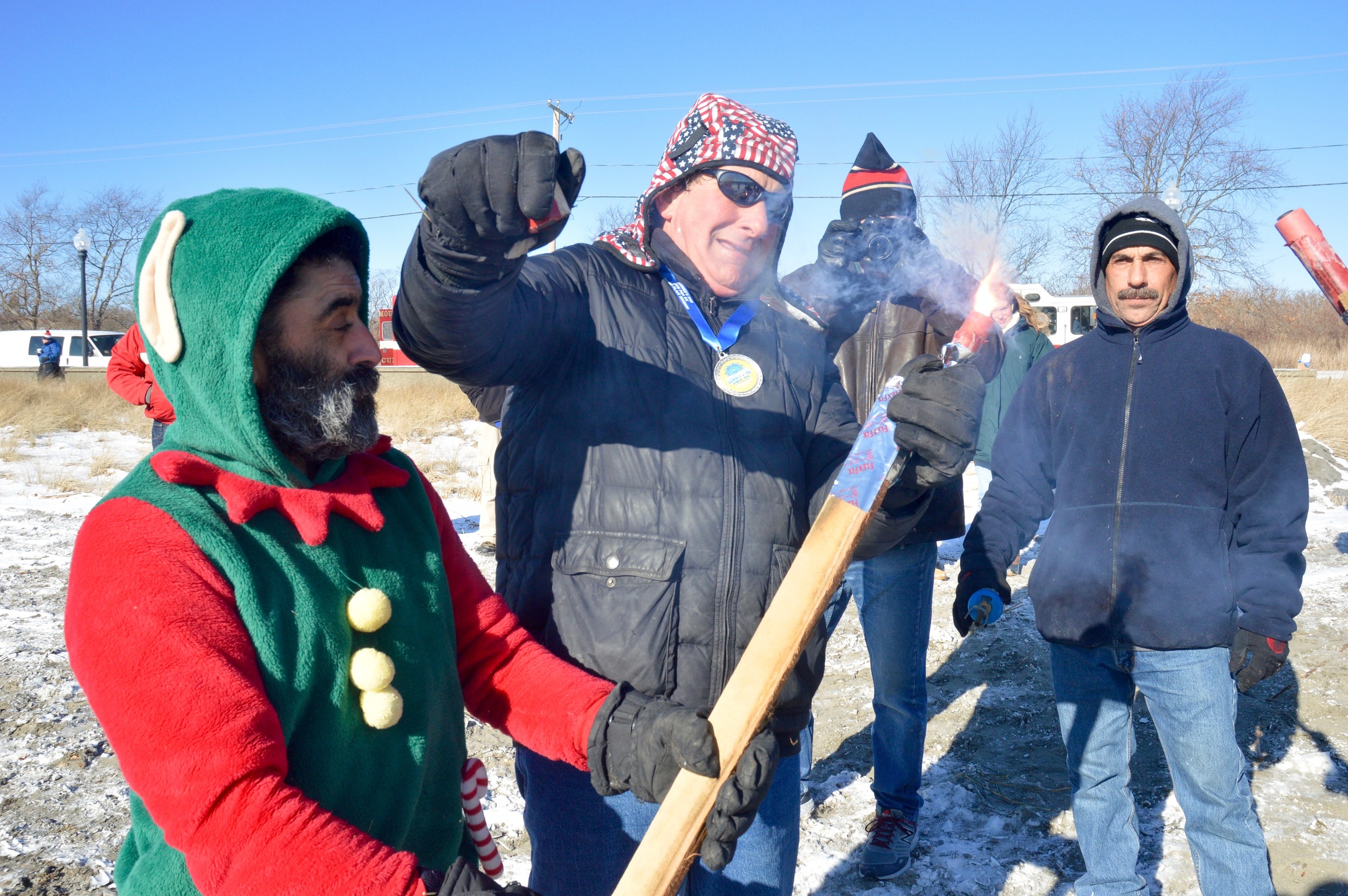 John Vitkevich (center), lights a torch for Chris Freitas (left) to be used for igniting the bonfire.