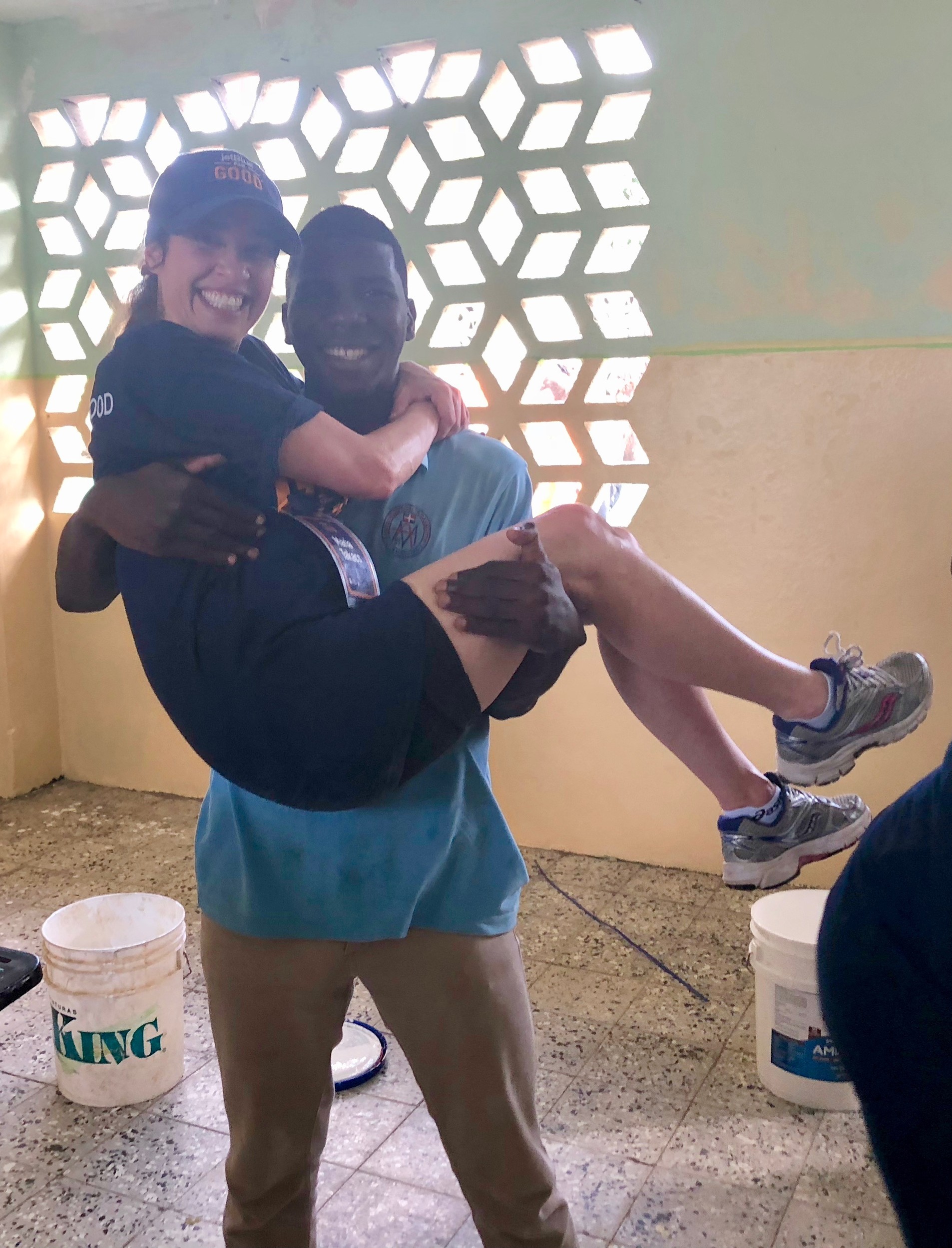 Thirteen-year-old Aneudis of the Dominican Republic picks up Maria Takacs before she and other volunteers painted the interiors of several classrooms.