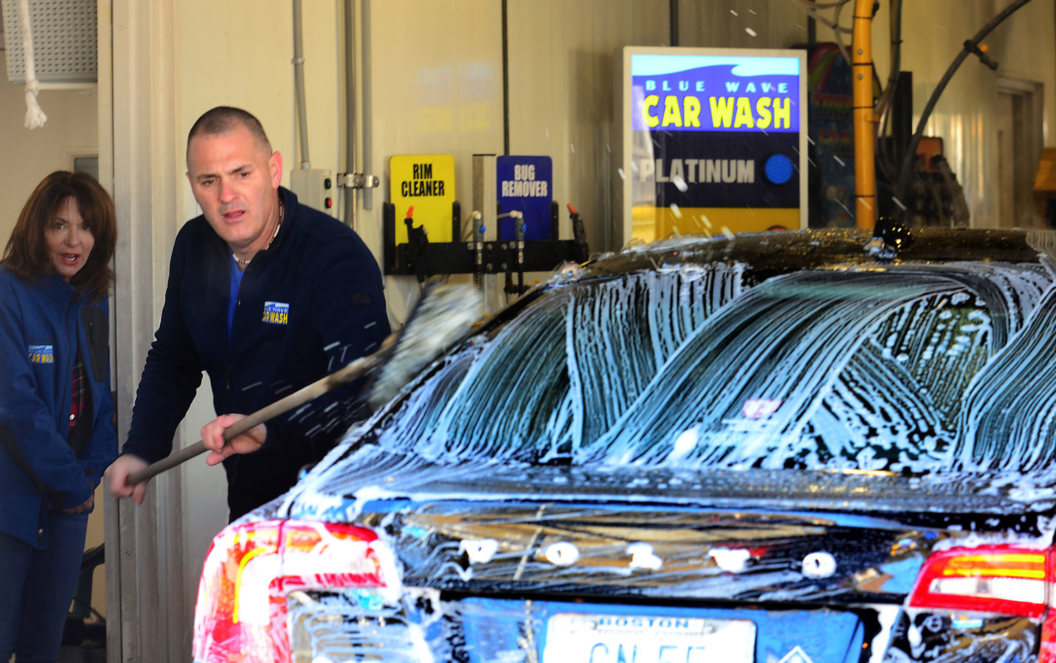 Blue Wave car wash owner Yvonne Blackman looks on as manager Pete Fabiano brushes down a client’s car with a soft cloth before it heads to the first stage of the car wash.