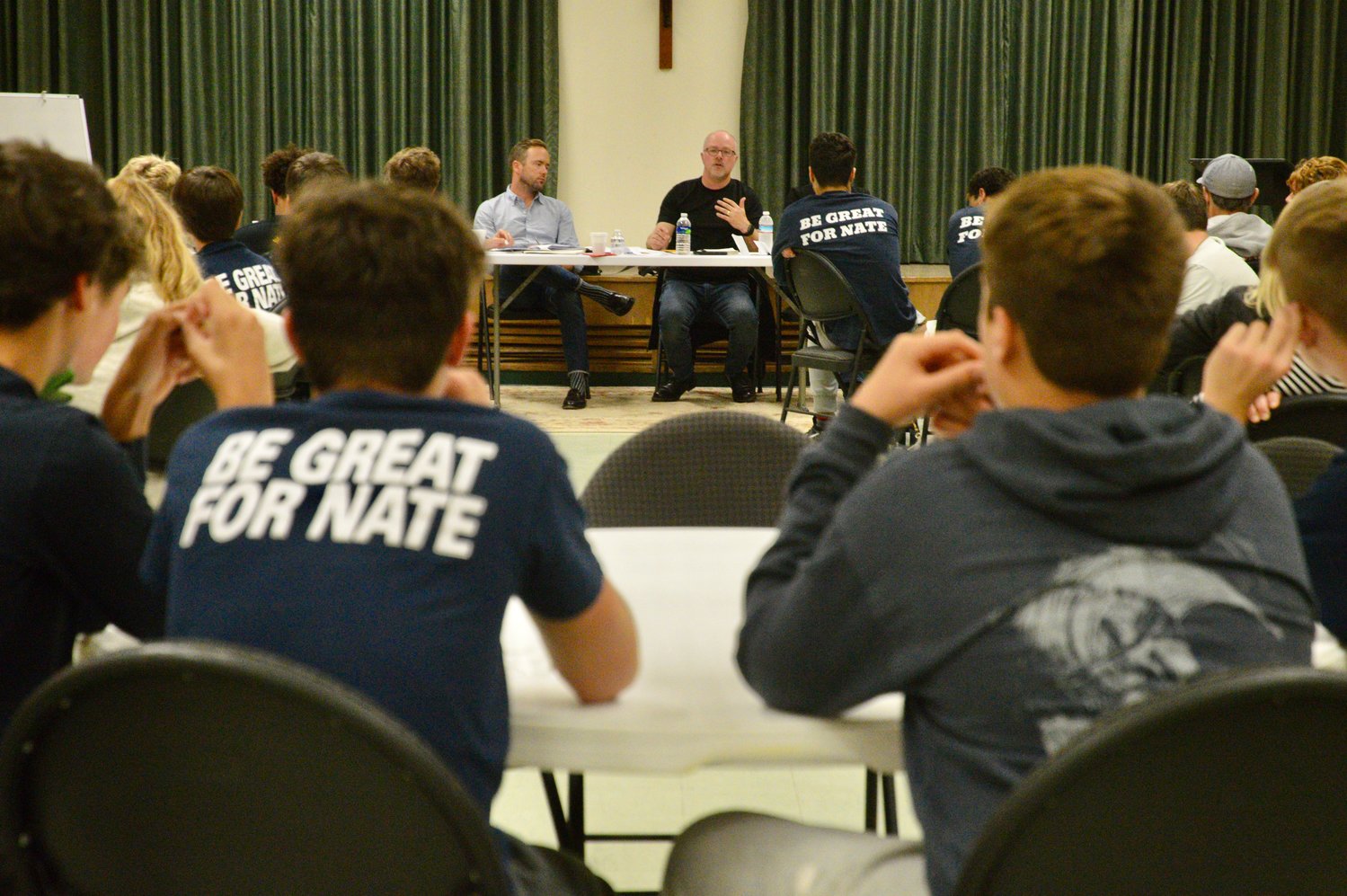 Co-director Erik Ewers talks about the upcoming documentary in front of more than 50 members of the community who came out to hear the PBS crew’s pitch Monday night at St. Barnabas Church. At left is his brother and co-director Chris Ewers. Some students were wearing “Be Great for Nate” shirts in honor of their late friend, Nate Bruno.