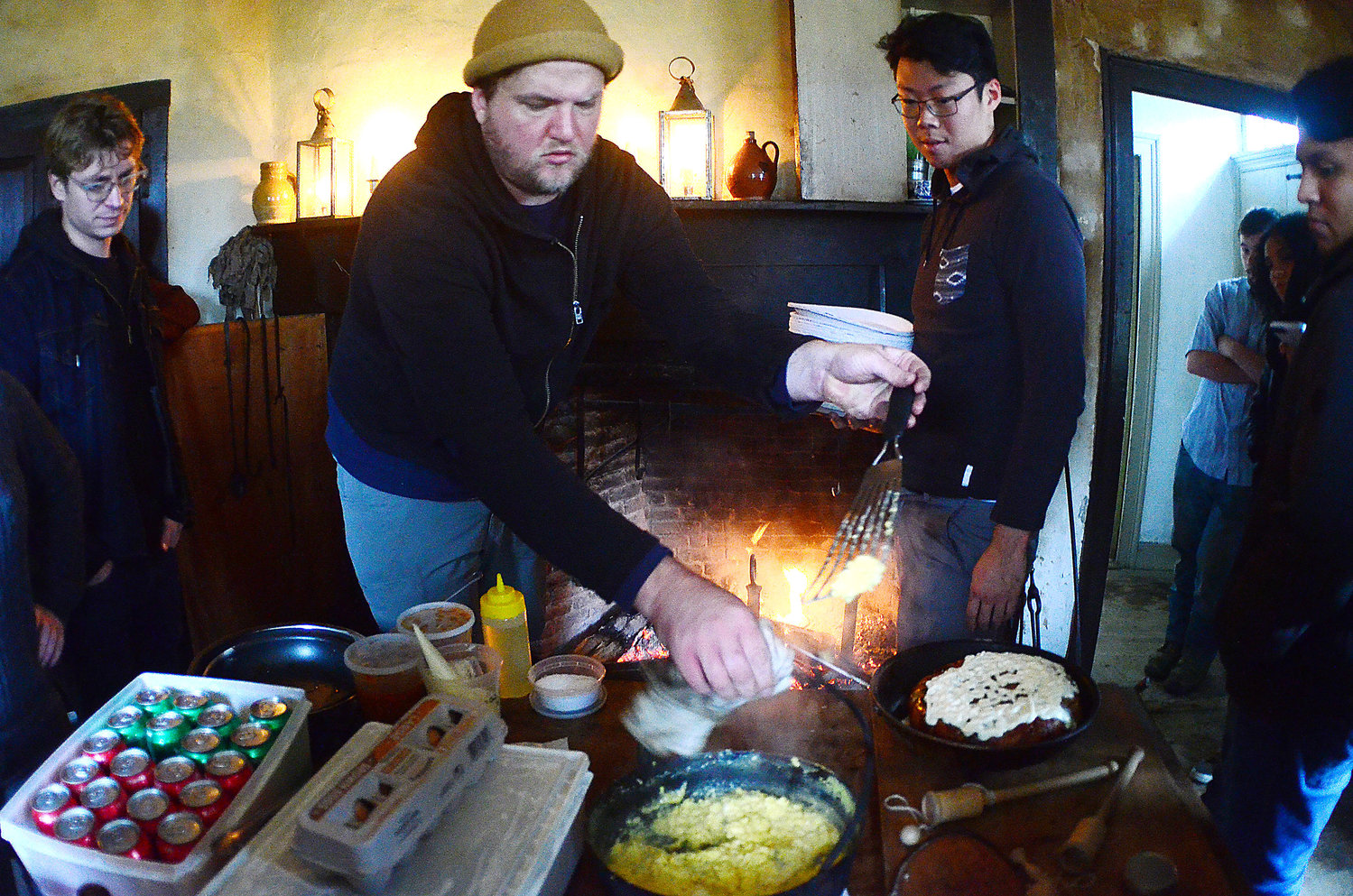 Restaurant owner Ben Sukle (middle) and John Ho (right) cook a meal on an historic open hearth for his Birch and Oberlin employees at Coggeshall Farm on Tuesday.