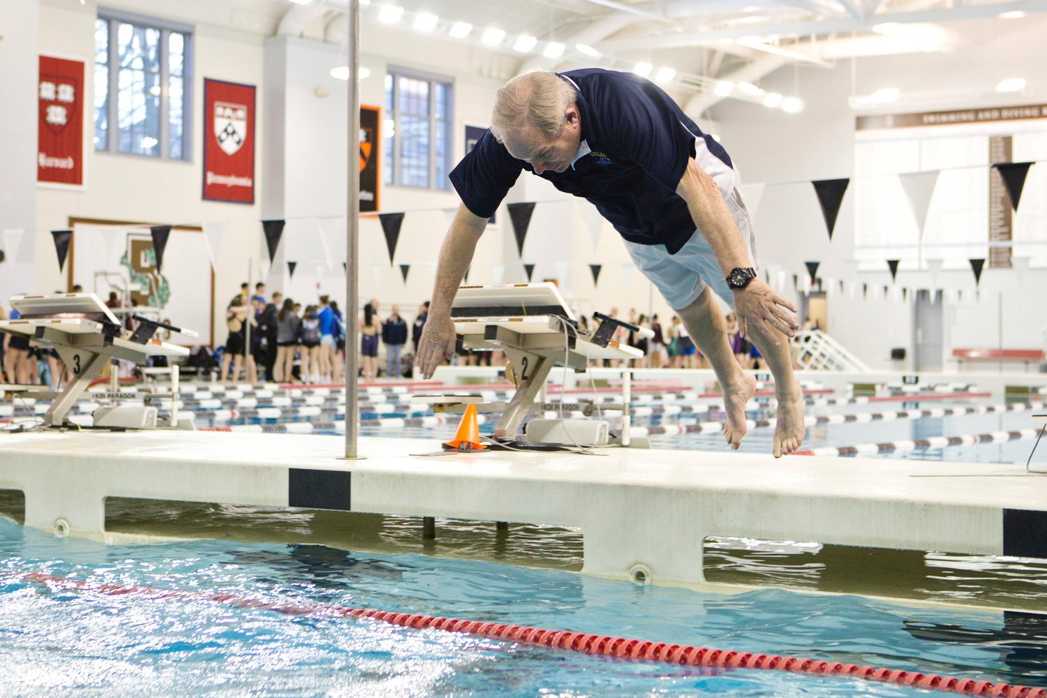 Barrington High School head coach Sandy Gorham takes a victory dive into the pool after his team won its sixth consecutive state championship, on Saturday.