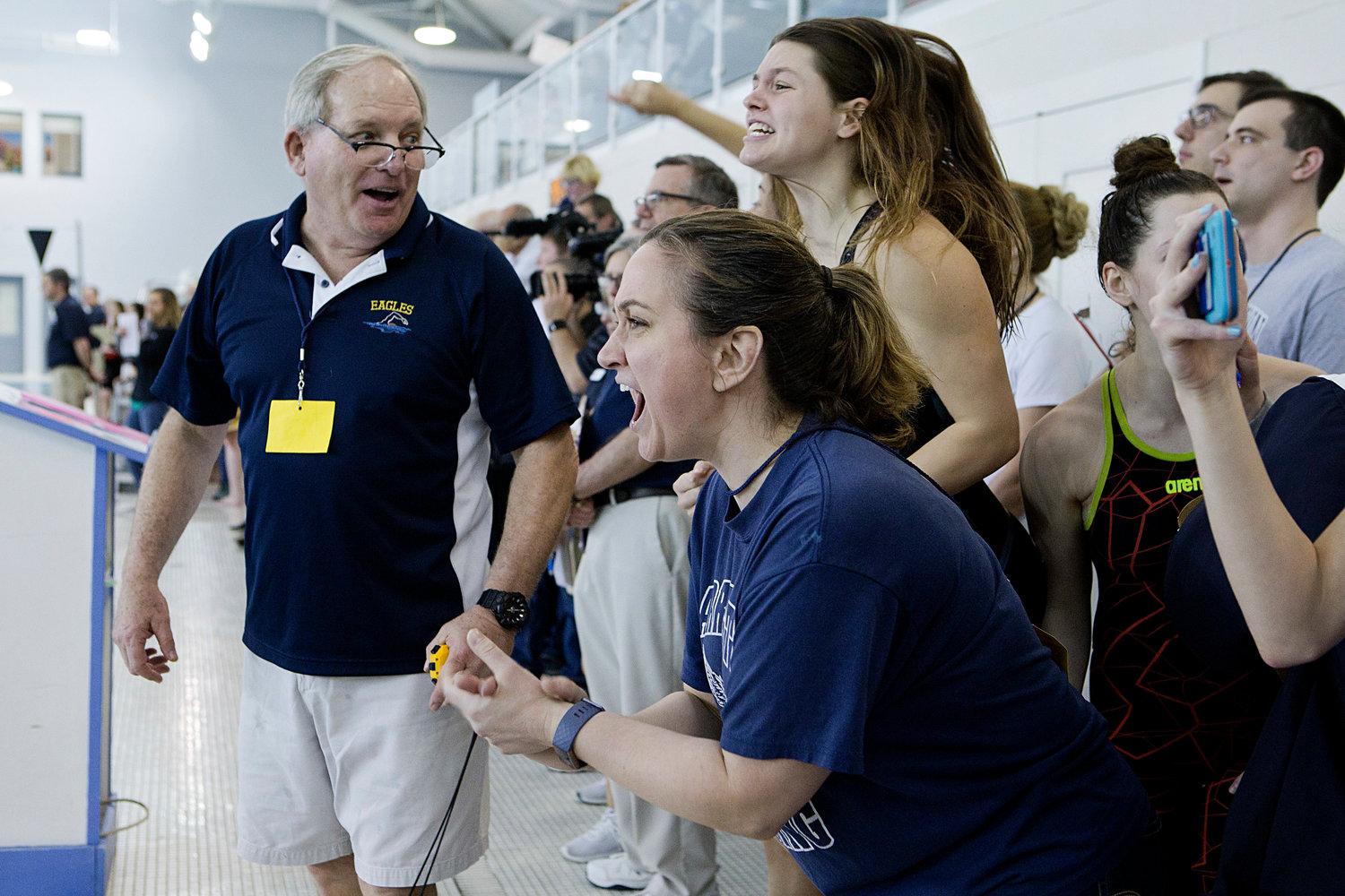 Barrington High School head coach Sandy Gorham (left) and assistant coach Jessica Mangione (right) cheer with their team as Sydni Diehl swims the final leg of the girls 400 yard freestyle relay at the state championship meet, Saturday.