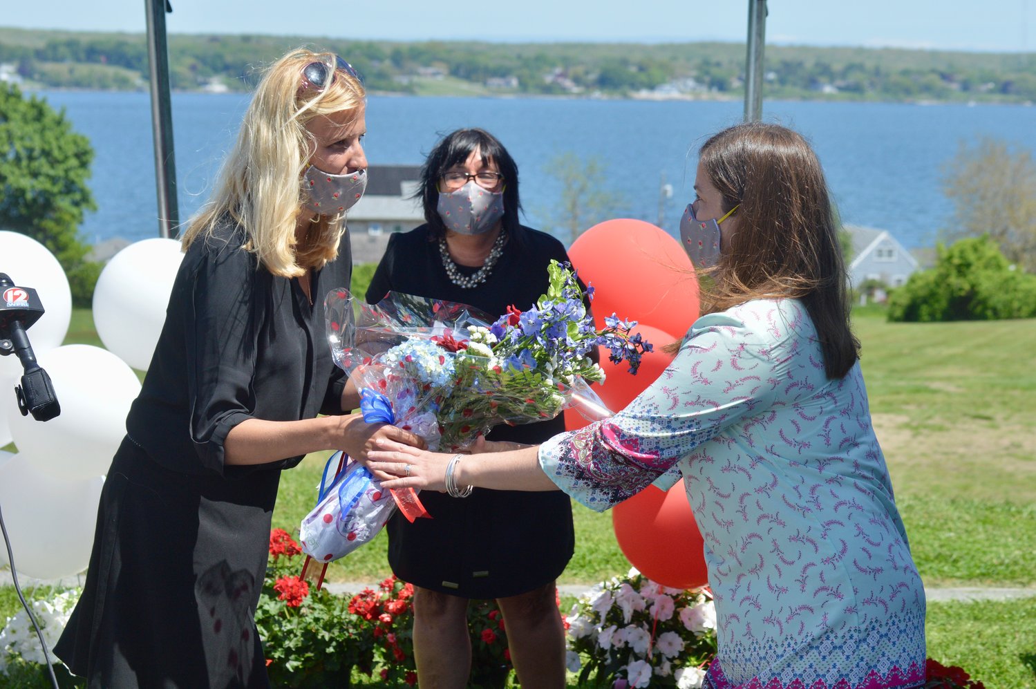 Elizabeth Russillo (left) the 2020 Rhode Island Teacher of the Year, presents a bouquet of flowers to her successor.