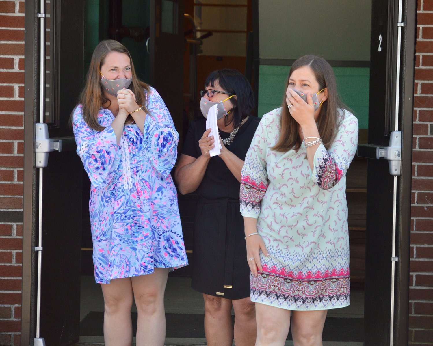 Ashley Adamson (right), a third-grade teacher at Hathaway School, reacts upon seeing a group of people greeting her outside the school during a surprise ceremony honoring her as the 2021 Rhode Island Teacher of the Year. At left is Victoria Travis, who team-teaches with Mrs. Adamson, with Hathaway School Principal Lisa Little in the middle.