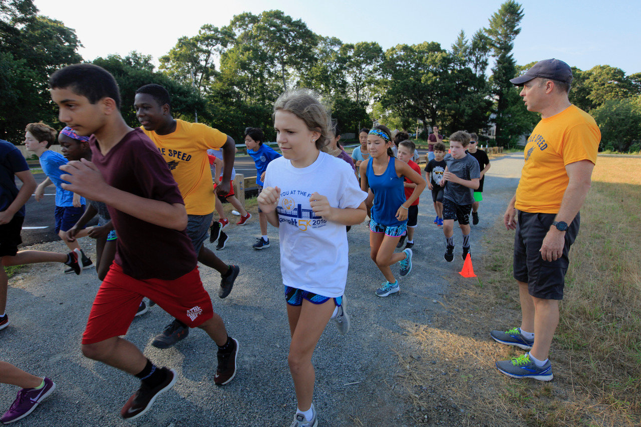 Barrington Middle School cross country and track coach Larson Gunness (right) is shown leading a summer running program practice in 2019.