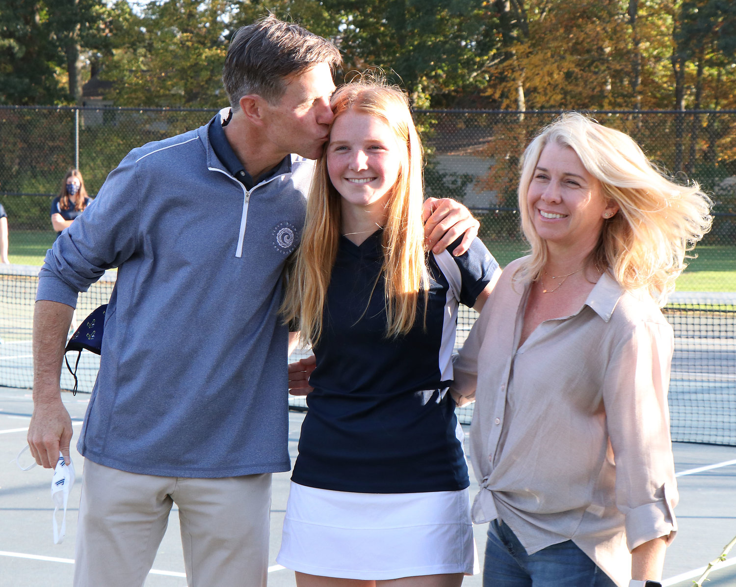 Meghan McDermott brings a flower and poses with parents Chris and Kim McDermott during a short senior ceremony at the courts on Friday afternoon.