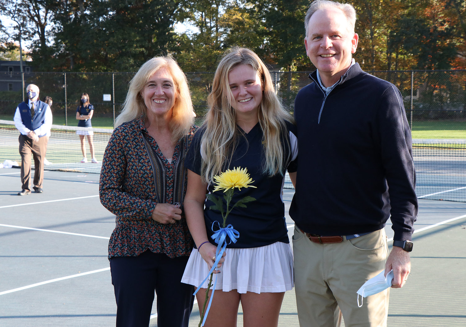 Caroline Maher brings a flower and poses with parents David and Pam Maher during a short senior ceremony at the courts on Friday afternoon.