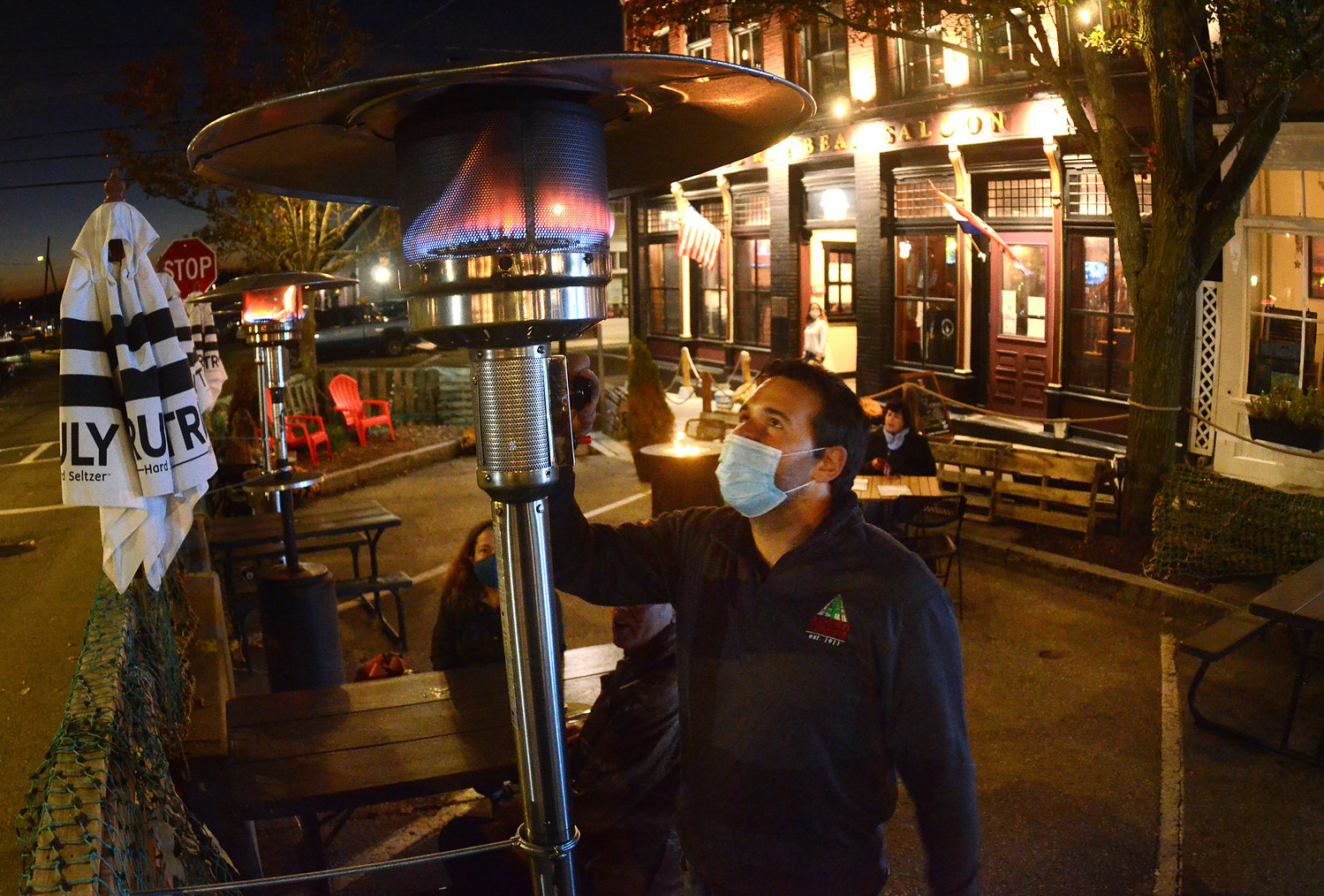 Judge Roy Bean Saloon owner Zach Rivers lights a patio heater for the restaurant's outdoor seating on State Street Tuesday night. The heaters were provided free to nearly two dozen Bristol businesses.