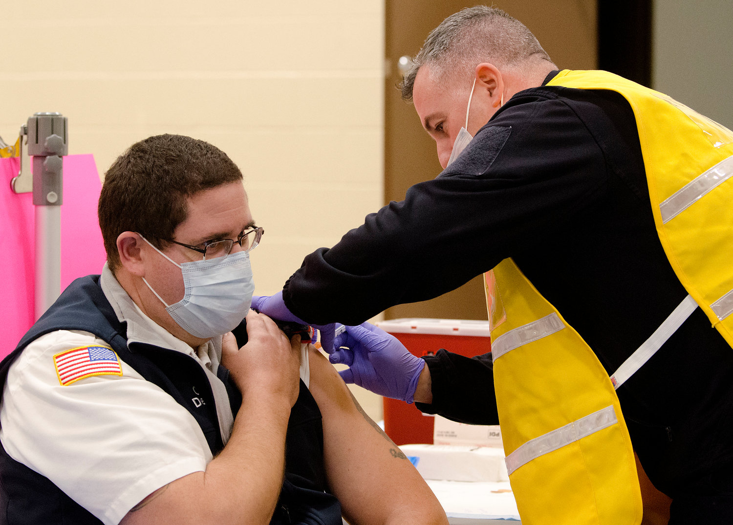 Bristol Fire Chief Mike DeMello receives a vaccination shot from Portsmouth resident and Middletown fireman Brian Defreitas.
