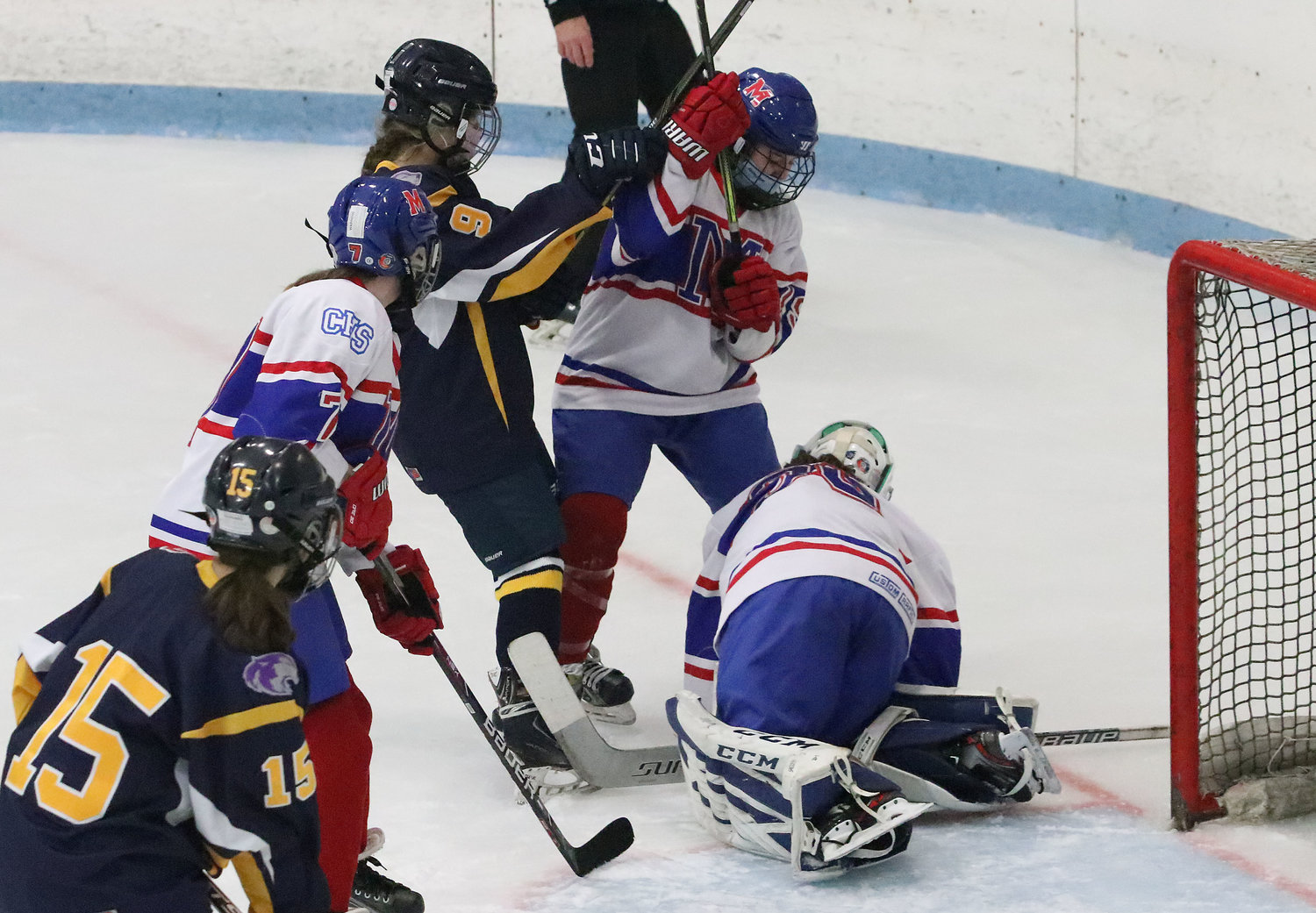 Brigid Carlin (left) and teammate Mia Phelps pressure the Mounties as goaltender Grace Davenport covers up the puck in the second period. 