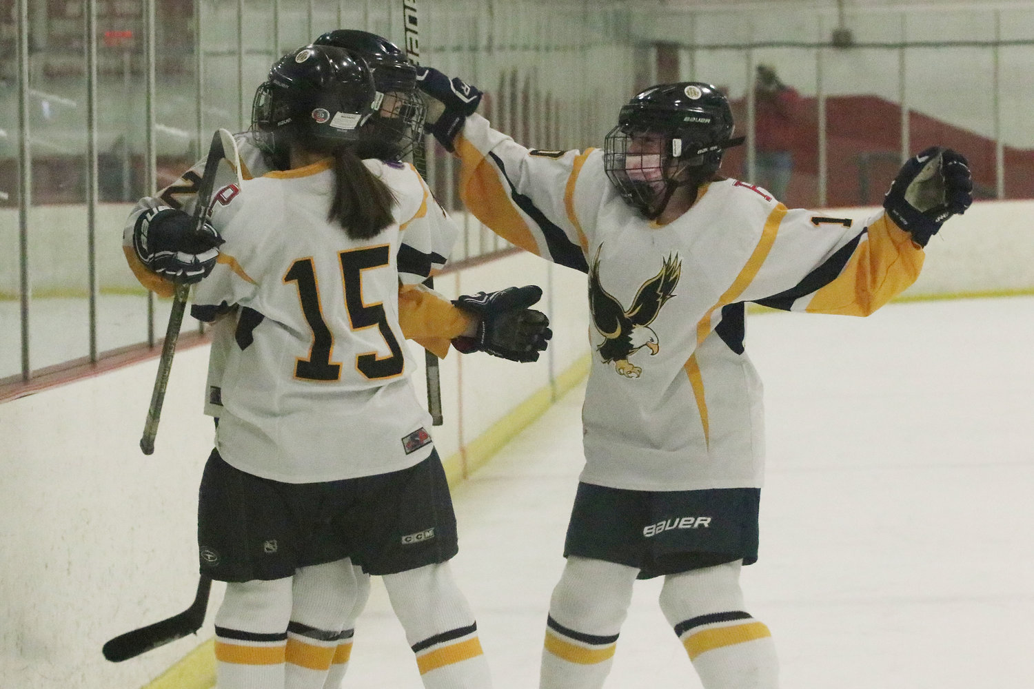 Brigid Carlin (left) and Mallory Cox (right) hug teammate Kat Barker after she scored the Eagles’ lone goal of the game in the second period of Game 2.