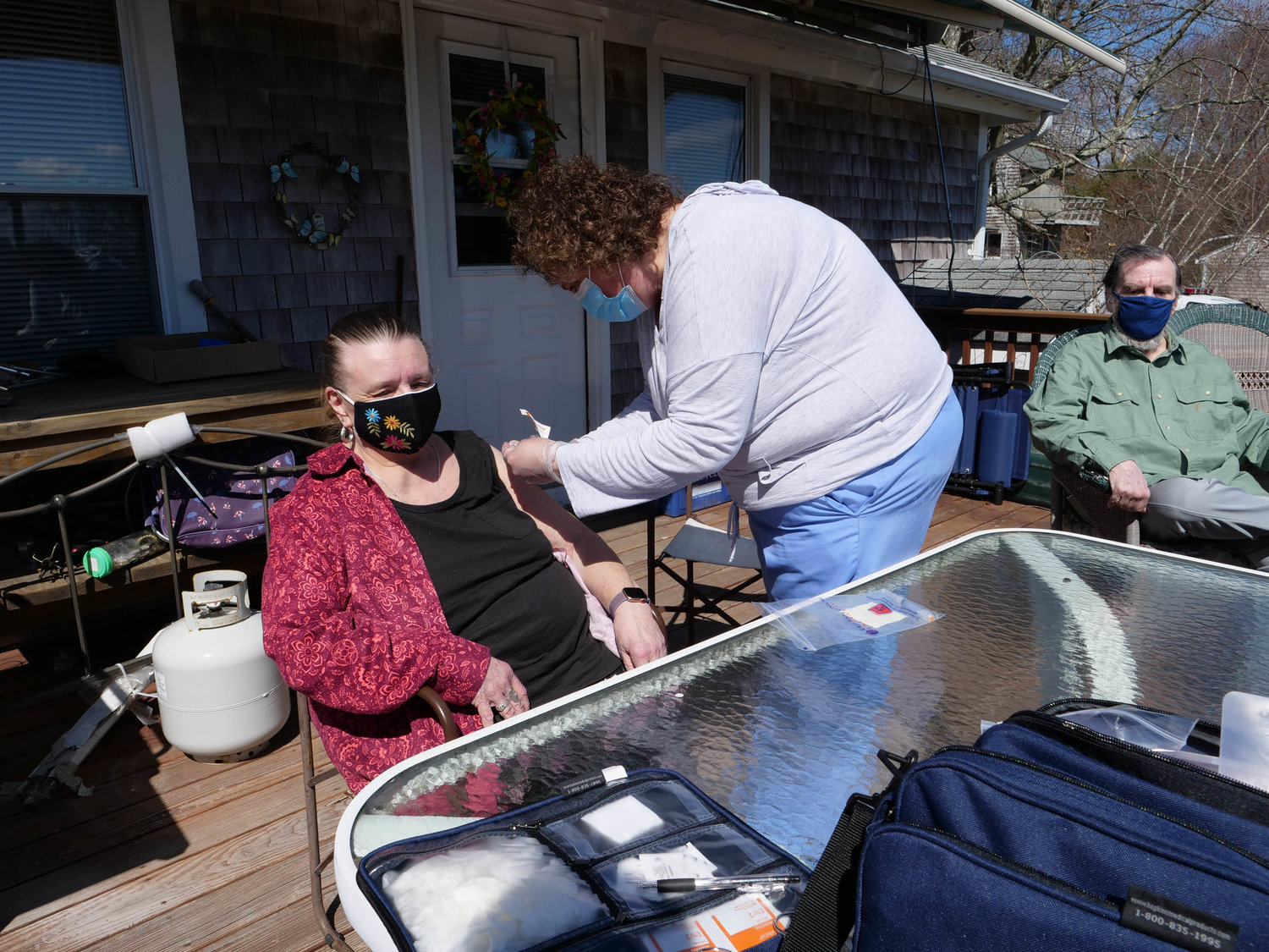 Prudence Island resident Linda Walsh receives a COVID-19 vaccination from registered nurse Lisa Pagliaro of PACE-RI, while her husband, Rick, waits his turn. Ms. Pagliaro made the trip to the island Thursday to administer the vaccine to the island’s homebound residents.
