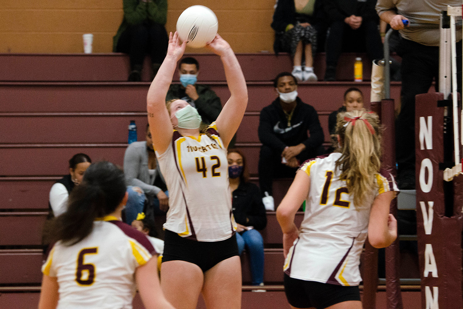 Gabby Piscani-Daugherty (left) and Molly Richardson (right) look on as teammate Madison Pelletier sets the ball. 