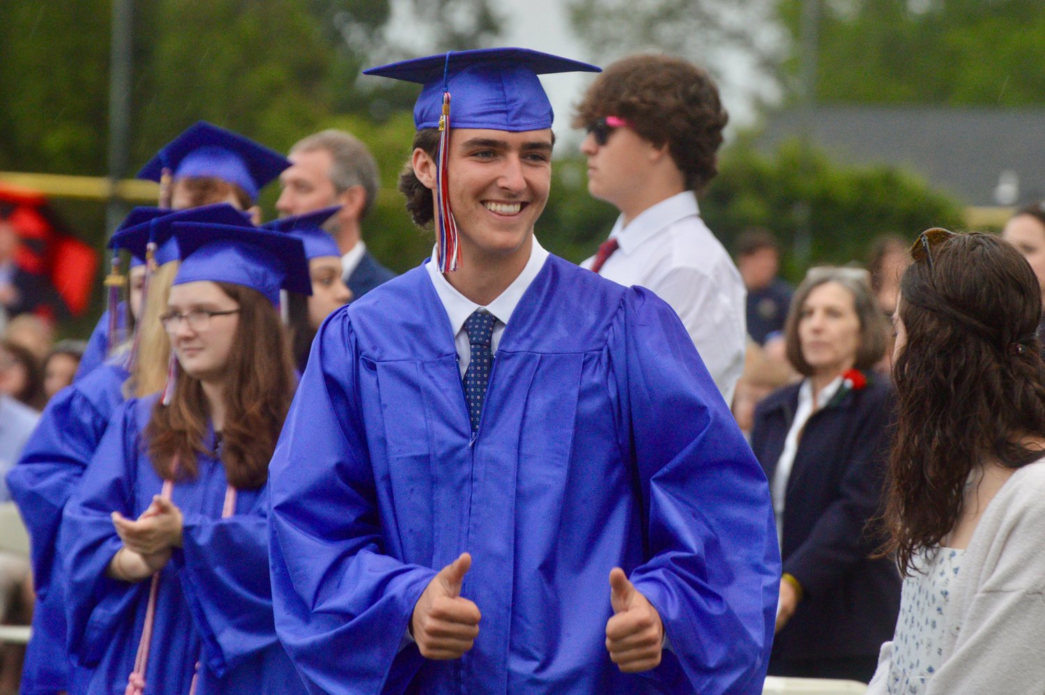 Hunter Tavares flashes a double thumbs-up to a photographer before walking on stage to collect his diploma.