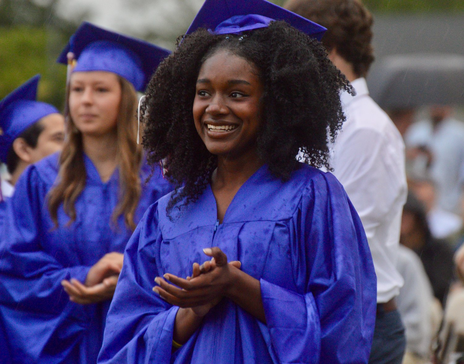 Zanai Williams claps for a fellow graduate receiving a diploma, just before collecting her own. Gentle rain began falling near the end of the ceremony, but it did not disrupt the event.