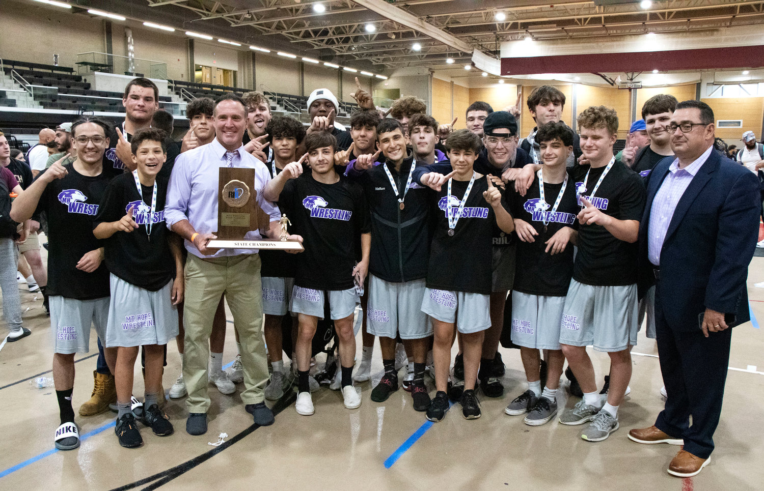 Head coach Eric Francis (mid-left) and assistant coach Mike Perreira (right) pose the the team and the state championship trophy after the meet.