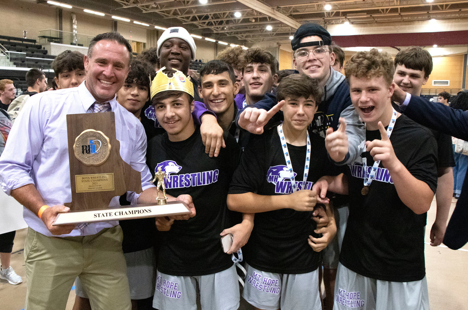 Coach Eric Francis and the team celebrate with the state championship trophy after the team won it's first ever wrestling state championship on Saturday.