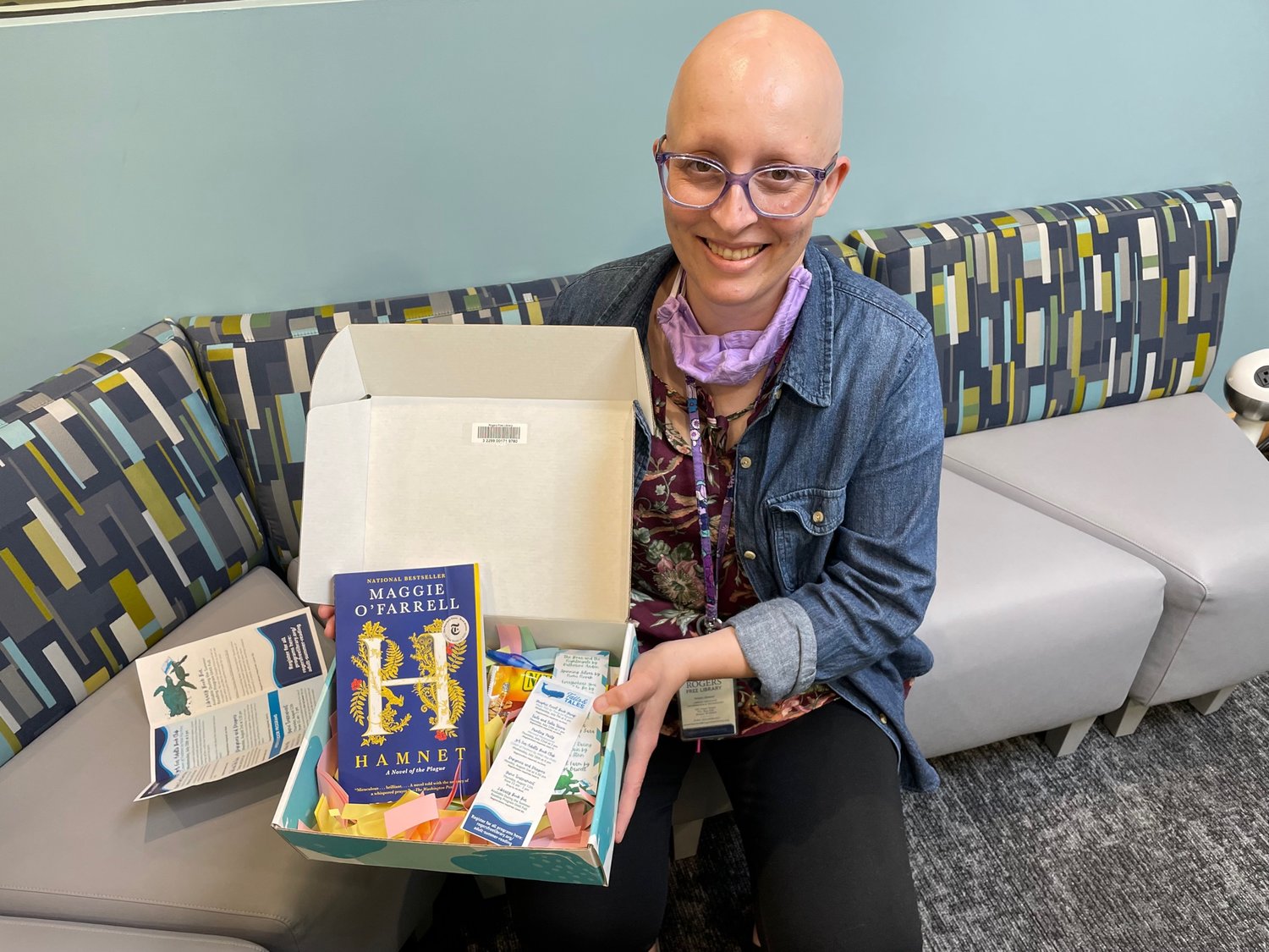 Information and technology librarian Kristin Amaral shows off a prototype of the library’s new subscription box, which will contain a snack and other treats along with a book, hand-selected for by a librarian, based on a form guests can fill out online.