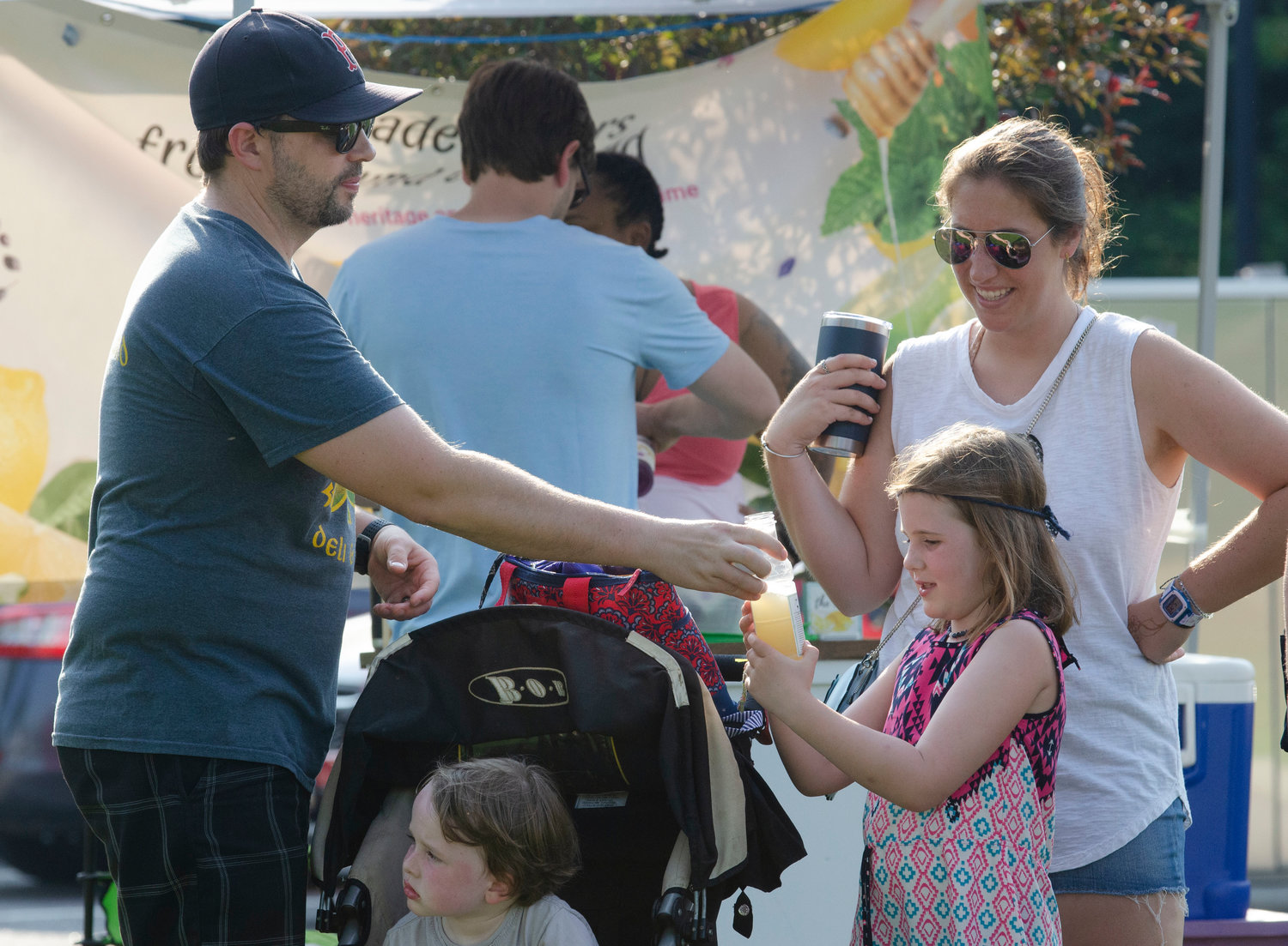 Alex Horvet hands his daughter Adelaine a lemonade, while Olivia Pawlyk looks on and James Horvet hangs out in a stroller during last week’s block party at Police Cove Park.