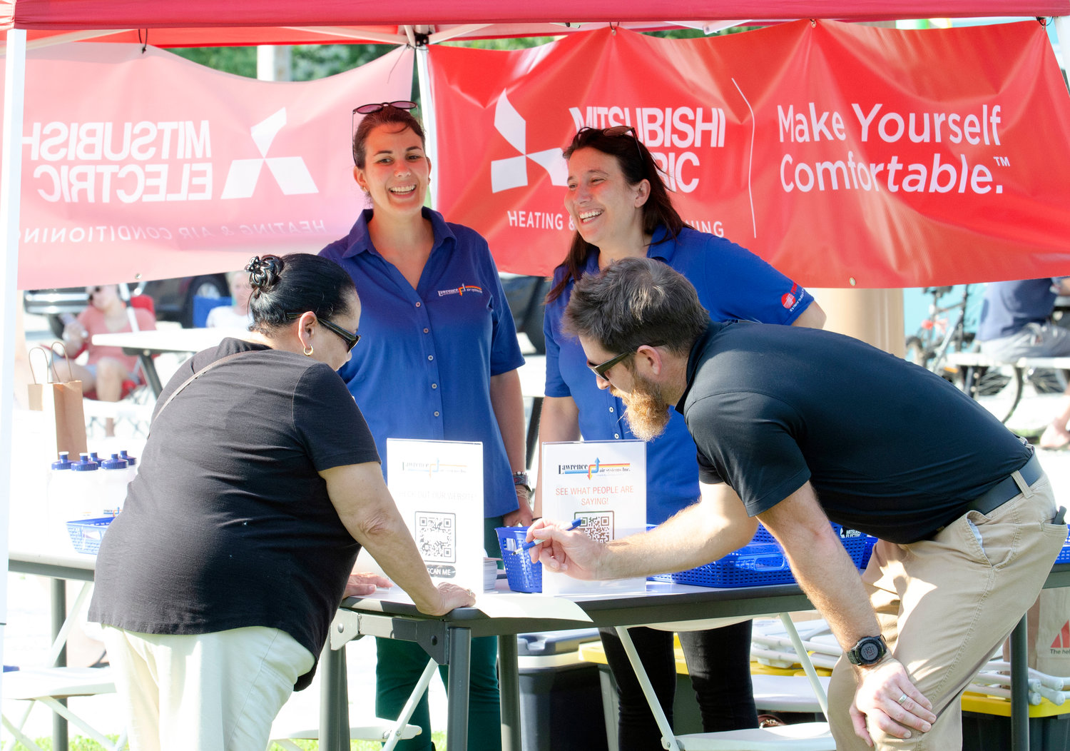 Lawrence Air Systems employees Patricia Silvia (mid left), Tricia Goulart and Aaron Lawrence chat with customer, Cecilia Lowell (left) during last Friday's block party at Police Cove Park.