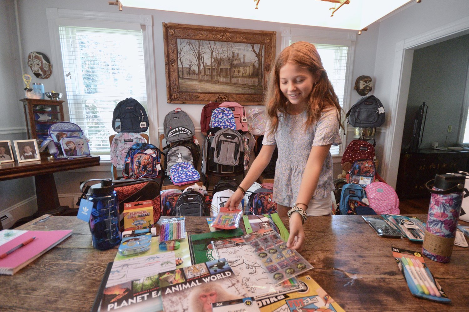 Willow Foregger, 13, sorts through items she will be putting inside backpacks (background) that will be donated to children in homeless shelters.