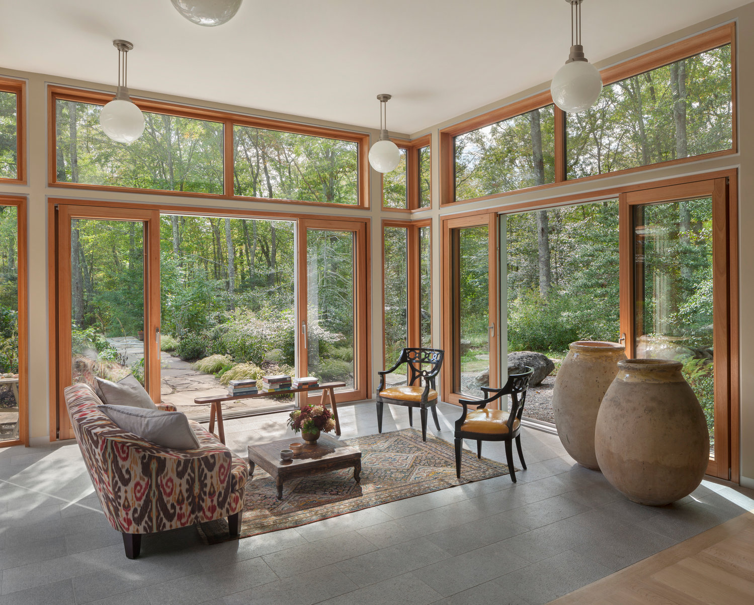 The garden room, or sunroom, showcases the simple elegance of the space, with walls of windows opening the home to the beautiful natural surroundings. This transitional space connects the entry courtyard to the primary living area.