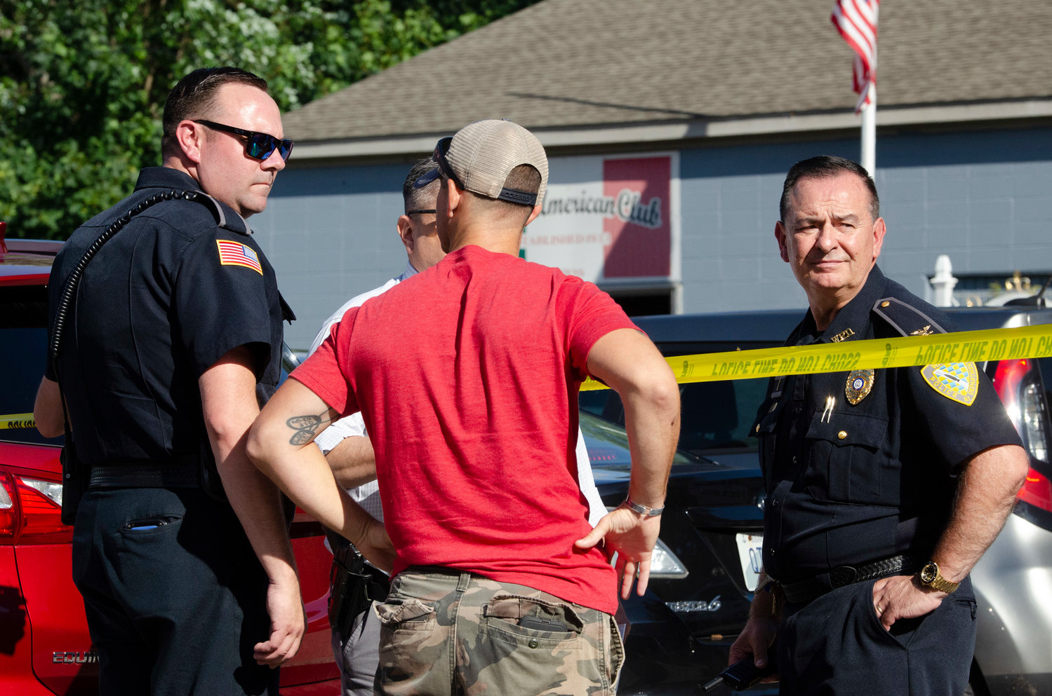 Warren Police Chief Roy Borges (right) and another officer speak with a bystander during an investigation of a shooting at the Italian American Club in Warren on Thursday afternoon.