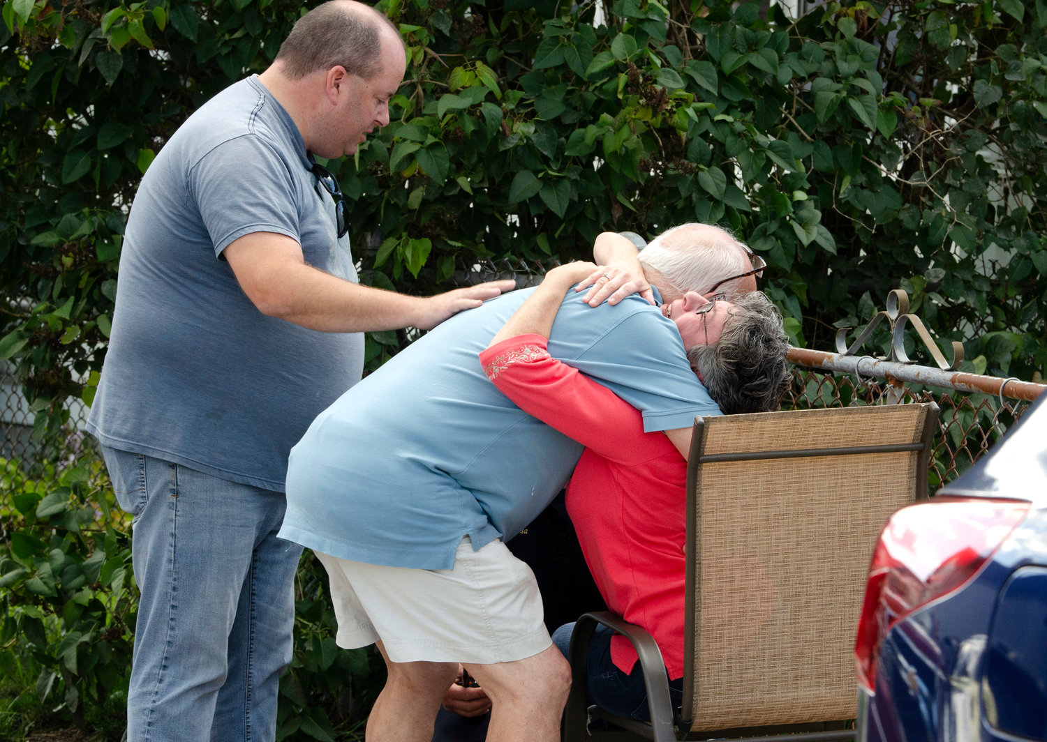 The family member of a shooting victim is comforted by men at the Italian American Club in Warren on Thursday.